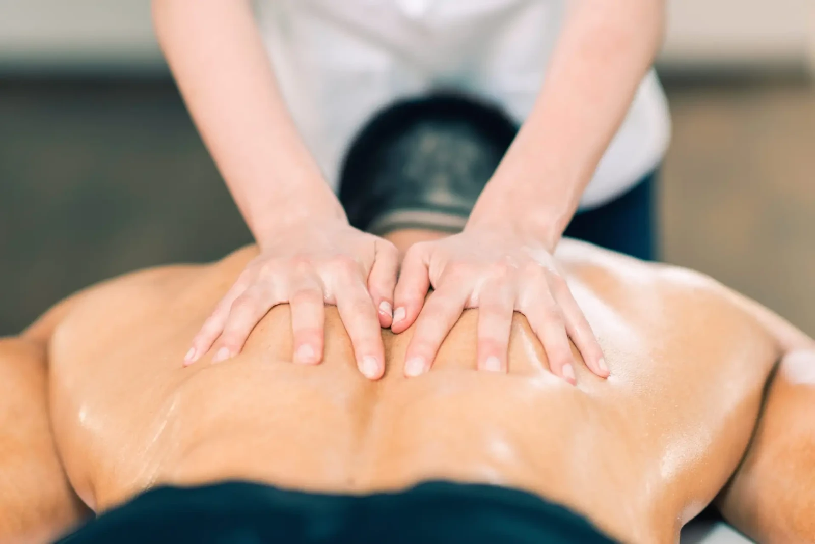 Therapist’s hands working slowly along a client’s back during in-home nerve compression therapy